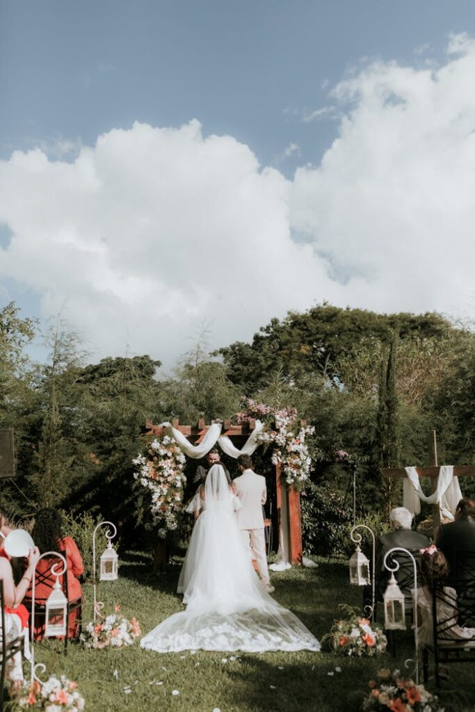 Beautiful outdoor wedding ceremony with floral arch and guests seated.